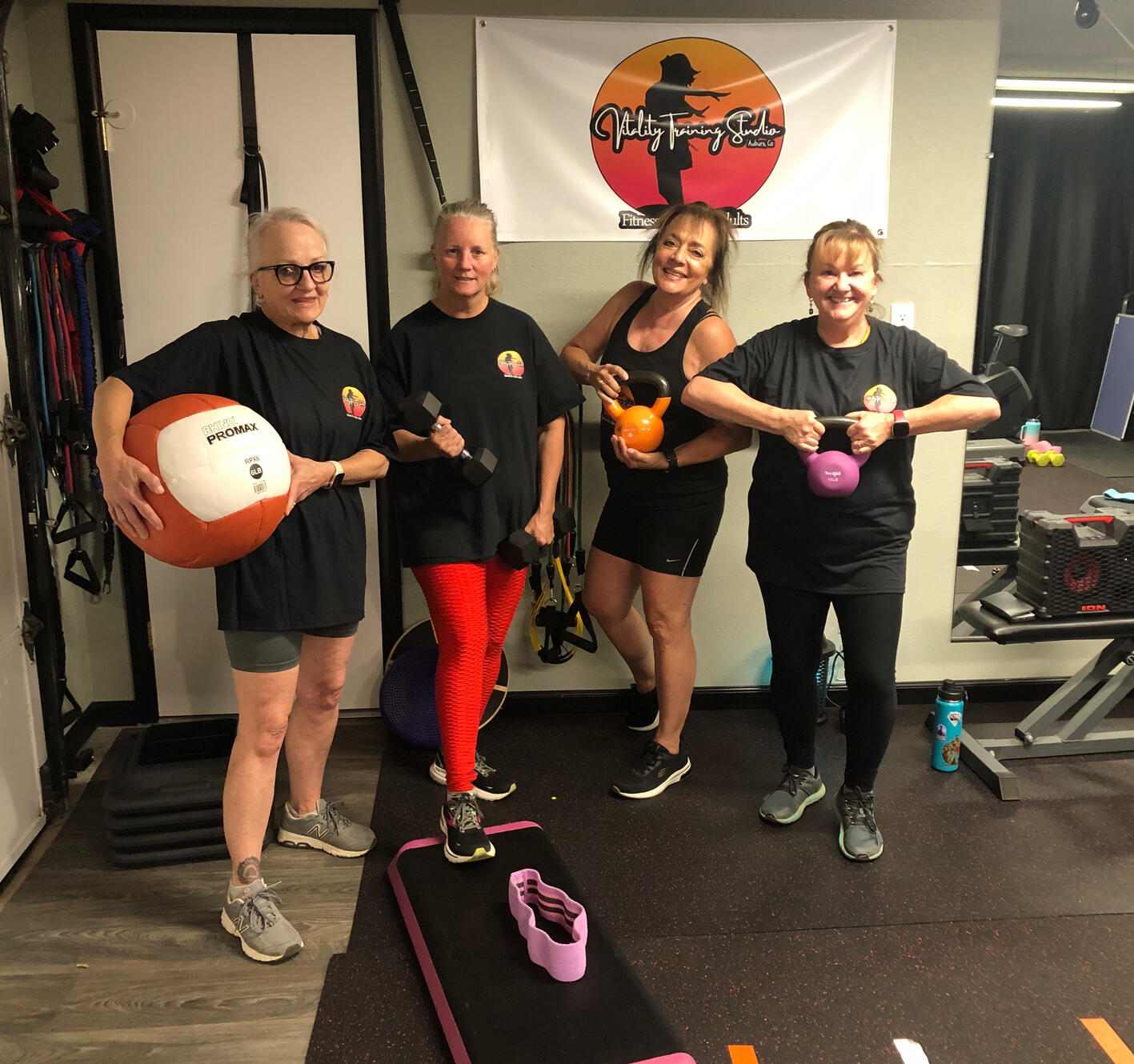 A group of women in an fitness studio holding workout equipment